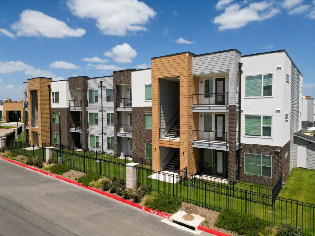 Three-story apartment buildings with balconies along the interior drive at Potranco Commons in West San Antonio